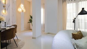 A modern bedroom with a large bed, a desk with chairs, and a bathroom with a marble wall and lighting fixtures. - Luxurious 1-bedroom apartment & 1 African-style bedroom (Dakar)