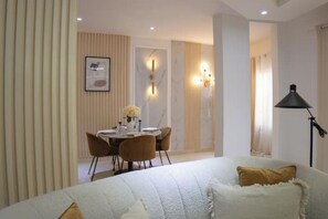 Ein modernes Hotelzimmer mit einem Bett, einer Essecke mit Tisch und Stühlen sowie einer Lampe.