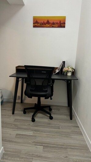 A corner office with a black desk, a black office chair, and a small potted plant on the desk.