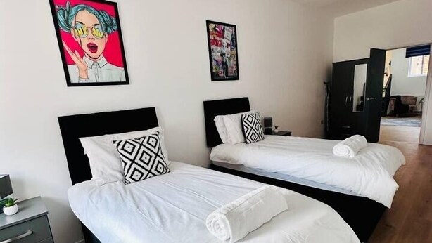 A modern hotel room with two single beds, a small bedside table, and a wardrobe. - Spacious 2-Bed Doncaster | Ideal for Teams (South Yorkshire)