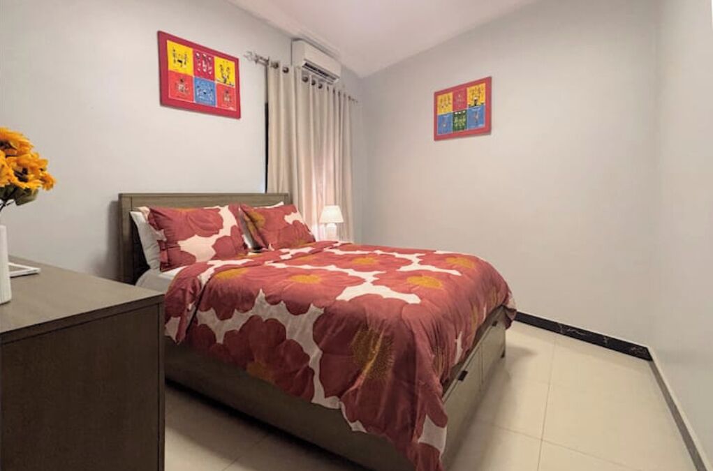 A bedroom with a bed, a nightstand, a lamp, and two wall art pieces.