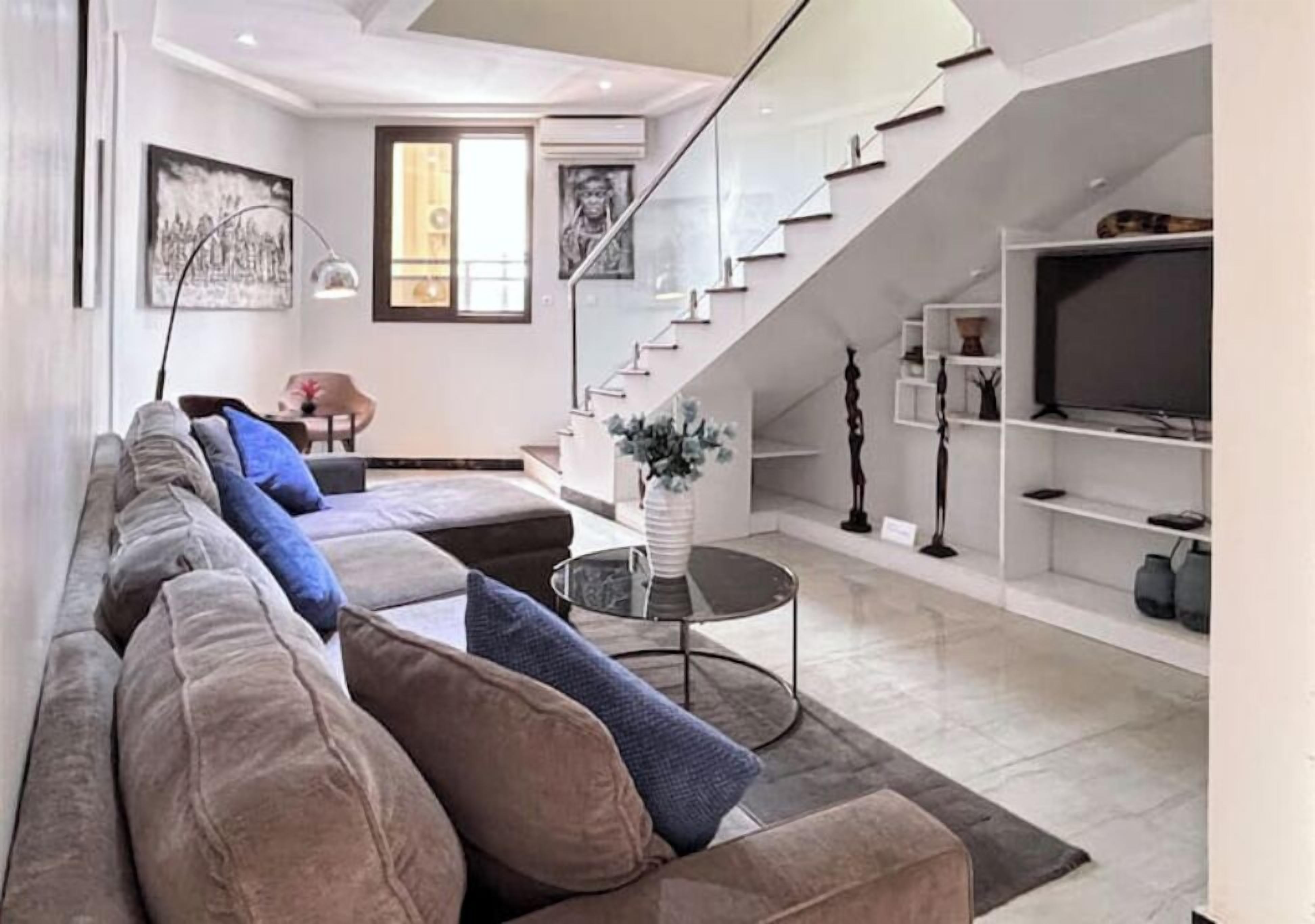 A modern living room with a sofa, a coffee table, and a staircase.