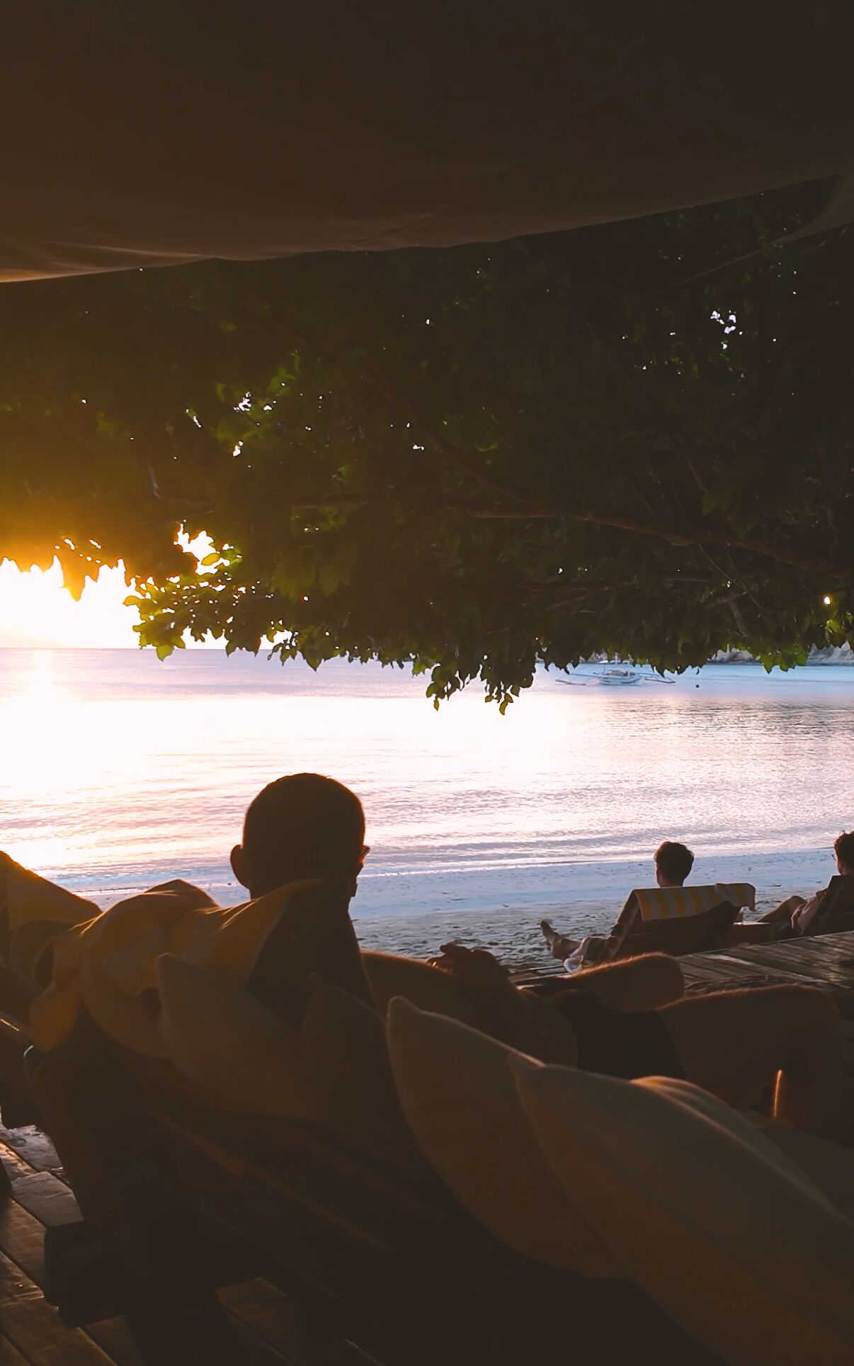 Un área de estar junto a la playa, con vista al atardecer sobre el agua.