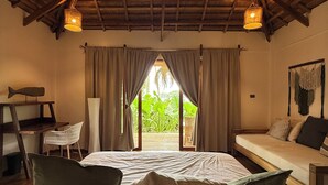 A bedroom with a wooden ceiling, a bed with pillows, a desk with a chair, and a window with curtains. - Baia beachfront boutique lodge (San Vicente)