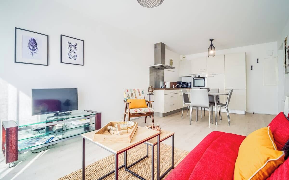 A modern living room with a glass coffee table, a red sofa, and a television.