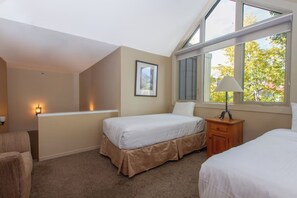 Una camera da letto con due letti, un comodino, una lampada, un quadro appeso alla parete e una finestra vista alberi.