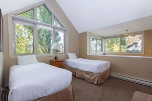 Ein Schlafzimmer mit zwei Betten, großen Fenstern, einer Lampe und einem Heizgerät.