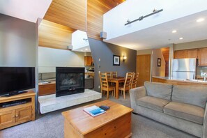 Ein modernes Wohnzimmer mit Kamin, Fernseher und Essbereich mit Holzmöbeln.