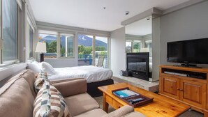A modern hotel room with a large bed, a sofa, a TV, and a fireplace. - Whistler Escape w/ Slope Access | Walk to Lifts & Village Fun | Near Gondola (Whistler)