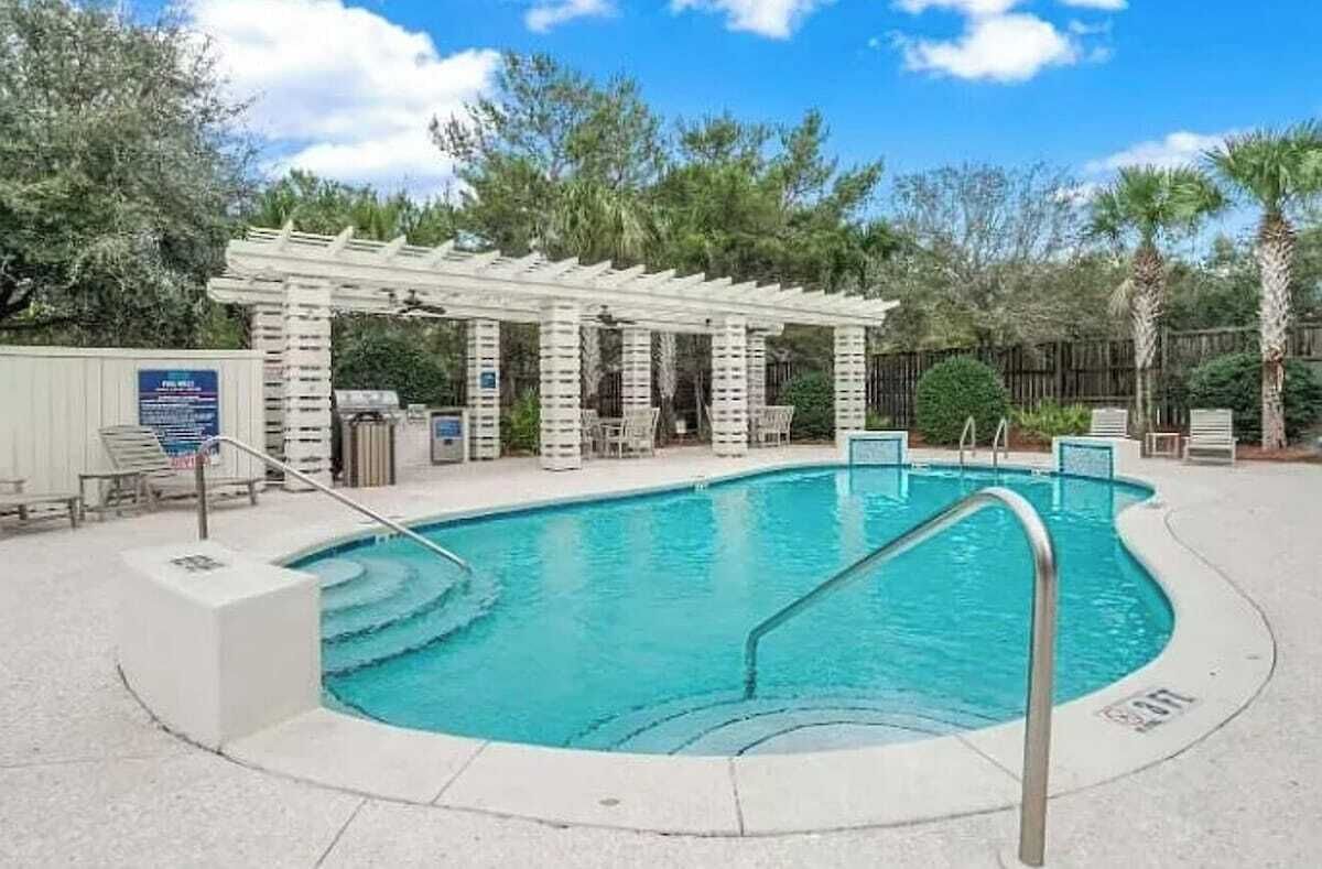 Ein Schwimmbecken mit einer Pergola und Liegestühlen.