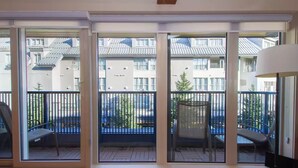 A modern apartment with large sliding glass doors leading to a balcony with a metal railing and a chair. - Premium Whistler Village Location | Large 3 Level Home Base | Private Hot Tub (Whistler)