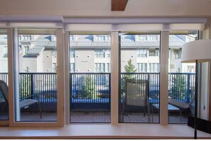 A modern apartment with large sliding glass doors leading to a balcony with a metal railing and a chair. - Premium Whistler Village Location | Large 3 Level Home Base | Private Hot Tub (Whistler)