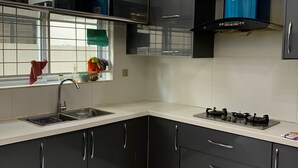 Een moderne keuken met zwarte kasten, een roestvrijstalen spoelbak, een gasfornuis en een afzuigkap.