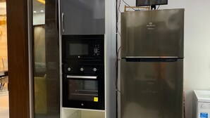 Een kleine keuken met een inbouwoven, magnetron en een roestvrijstalen koelkast.