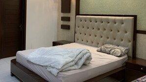 Een slaapkamer met een bed, een plafondventilator, inbouwspots, een wandlamp en een deur.