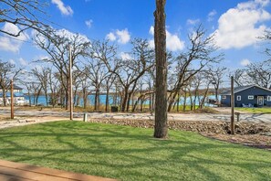 Una proprietà sul lago con prato verde, terrazza in legno e una casa con pontile.