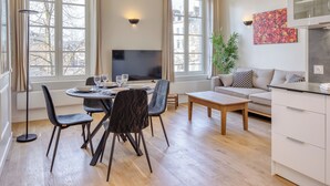 Ein modernes Wohnzimmer mit Essbereich, einer Couch, einem Fernseher und einer Pflanze.