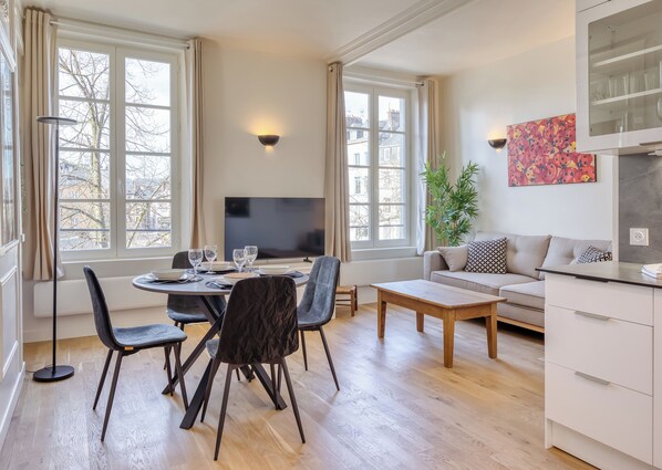 Ein modernes Wohnzimmer mit Essbereich, einer Couch, einem Fernseher und einer Pflanze.