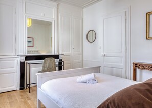 Ein Hotelzimmer mit Bett, Schreibtisch, Stuhl, Spiegel und Kommode.