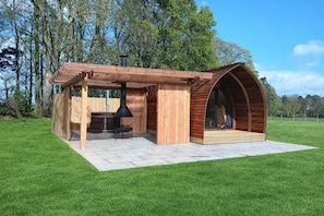 A wooden outdoor structure with a barbecue area and a covered seating space.