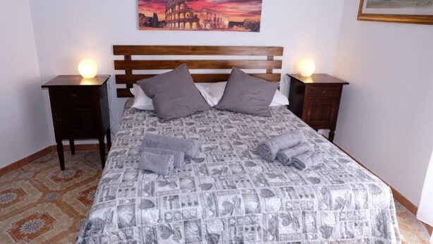 Ein Bett mit einem gemusterten Überwurf, zwei Kissen und zwei Nachttische mit Lampen.