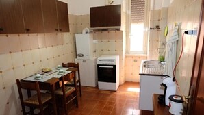 Eine kompakte Küche mit Esstisch, Stühlen, Kühlschrank, Backofen und Spüle.