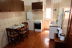 A compact kitchen with a dining table, chairs, a refrigerator, an oven, and a sink. - Casa Ariel - Cozy Apartment with Terrace in the Heart of Monteverde (Roma)
