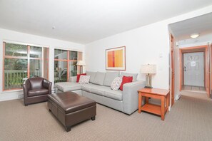 A modern living room with a sectional sofa, a leather armchair, and a wooden side table.