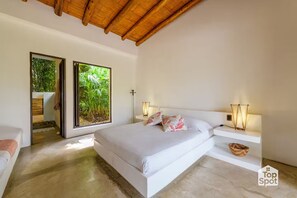 Une chambre moderne avec un grand lit, deux tables de chevet avec des lampes, une vue sur la verdure grâce à une porte coulissante, et un plafond en bois.