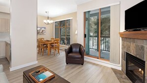 Una sala de estar moderna con chimenea, televisor y zona de comedor con mesa y sillas.