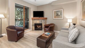 Una sala de estar moderna con chimenea, sofás de cuero y un televisor de pantalla plana.