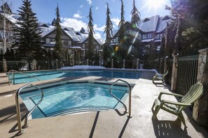 Ein Pool mit Metallgeländern und einem Liegestuhl, umgeben von Bäumen und Gebäuden.