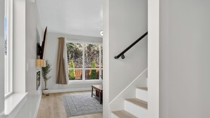 A modern interior with a staircase, a window with a view of a garden, and a wooden floor. - Nampa`s New Nest -The Renaissance (Nampa)