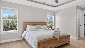 A bedroom with a wooden bed, large windows, and a ceiling fan. - Nampa`s New Nest -The Renaissance (Nampa)