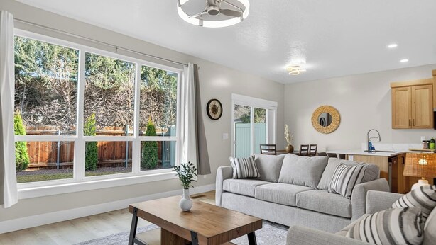 A modern living room with a large window, a dining area, and a kitchen. - Nampa`s New Nest -The Renaissance (Nampa)