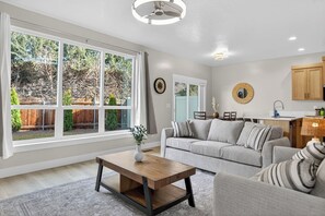 Una sala de estar moderna con un ventanal grande, una zona de comedor y una cocina.