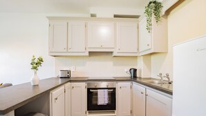 A kitchen with white cabinets, a built-in oven, a sink, and a countertop. - 3-Bedroom Apartment in Dunaras Village (Galway)