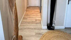 A hallway with a wooden sculpture, a woven rug, and a mounted clock on the wall. - Lovely 3-room apartment with swimming pool in Puteaux (Puteaux)