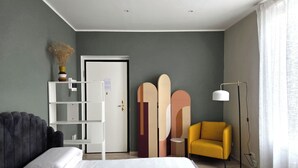 Un dormitorio moderno con una cama, un sillón amarillo, un estante blanco y una puerta.