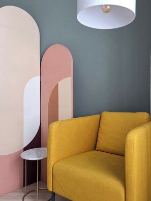 Ein gelber Sessel in einem Zimmer mit modernem Design, mit rundem Tisch und abstrakter Wandkunst.