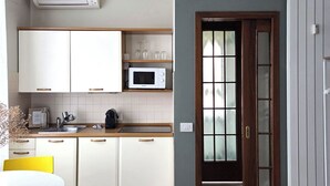 Una cocina con armarios blancos, un microondas y una mesa de comedor con sillas amarillas.
