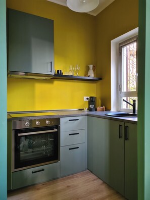 Eine Küche mit Backofen, Kaffeemaschine und einem Fenster mit schmiedeeisernen Gitterstäben.