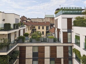 A modern residential building with multiple balconies, a mix of flat and sloped roofs, and a variety of vegetation. - deluxe apartment (Milan)
