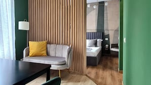 Ein modernes Hotelzimmer mit einer Couch, einem Bett, einem Schreibtisch und einer Lampe.