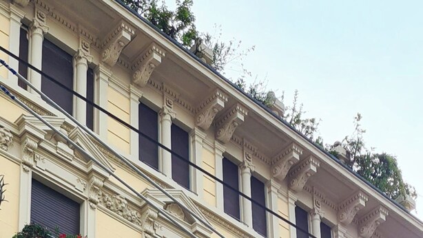 Ein mehrstöckiges Gebäude mit aufwendigen architektonischen Verzierungen, darunter dekorative Balkone und Fenster.
