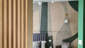 Ein modernes Schlafzimmer mit Bett, Stuhl, Nachttisch und einem besonderen Wanddesign.