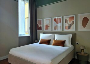 A hotel room with a large bed, a window with curtains, and abstract art on the wall. - Serendipity Apartments Missori (Milan)