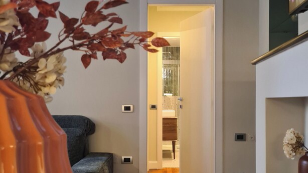 A modern living room with a blue sofa, a decorative orange vase, and an air conditioning unit on the wall. - Serendipity Apartments Missori (Milan)