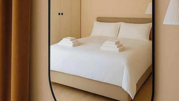 Een slaapkamer met een bed, een hanglamp en een wandlamp.