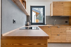 Eine moderne Küche mit Holzausbau, einem eingebauten Herd und einem Fenster mit Blick auf eine Holzkonstruktion.